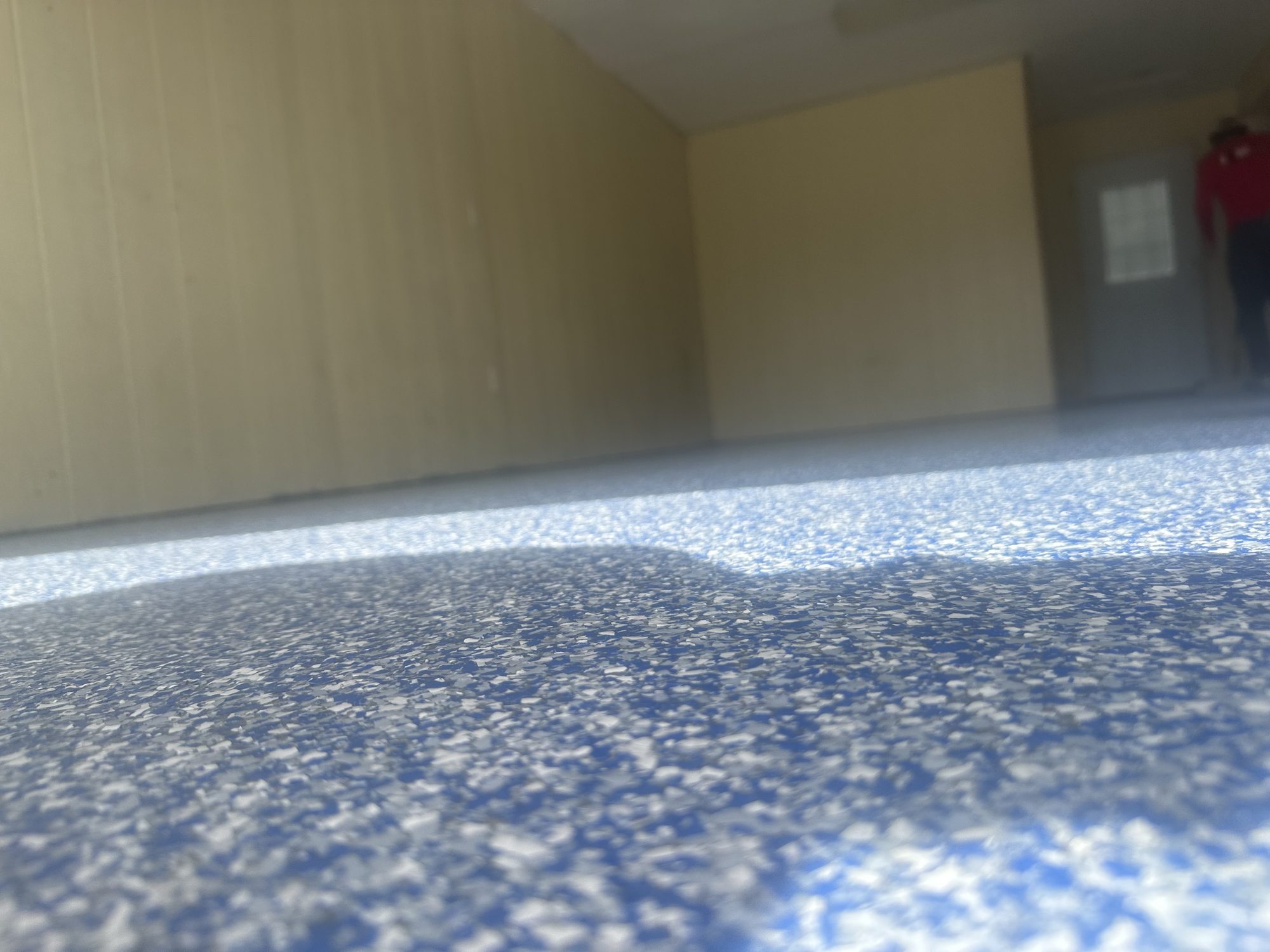 Blue and white flake epoxy floor in a commercial room, camera low at the slab, Huntsville, AL
