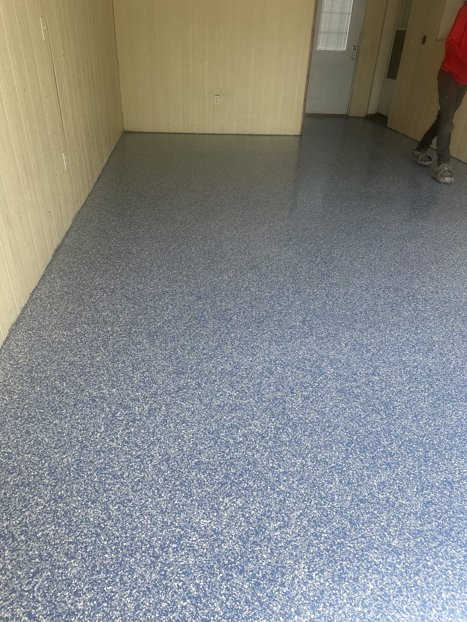 Blue and gray flake epoxy floor along a corridor with panelled walls and a white door, Huntsville, AL