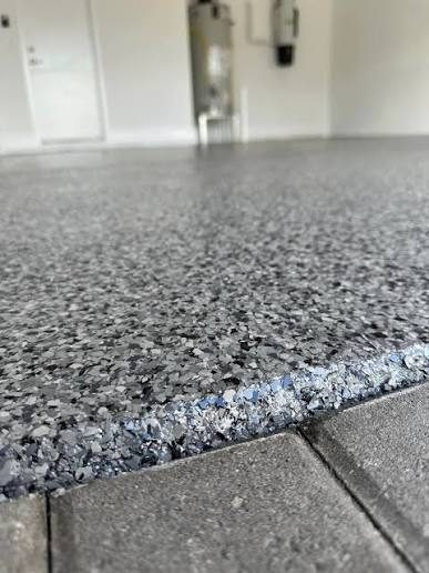 Gray flake epoxy floor meeting a concrete step edge, interior with white walls, Huntsville, AL