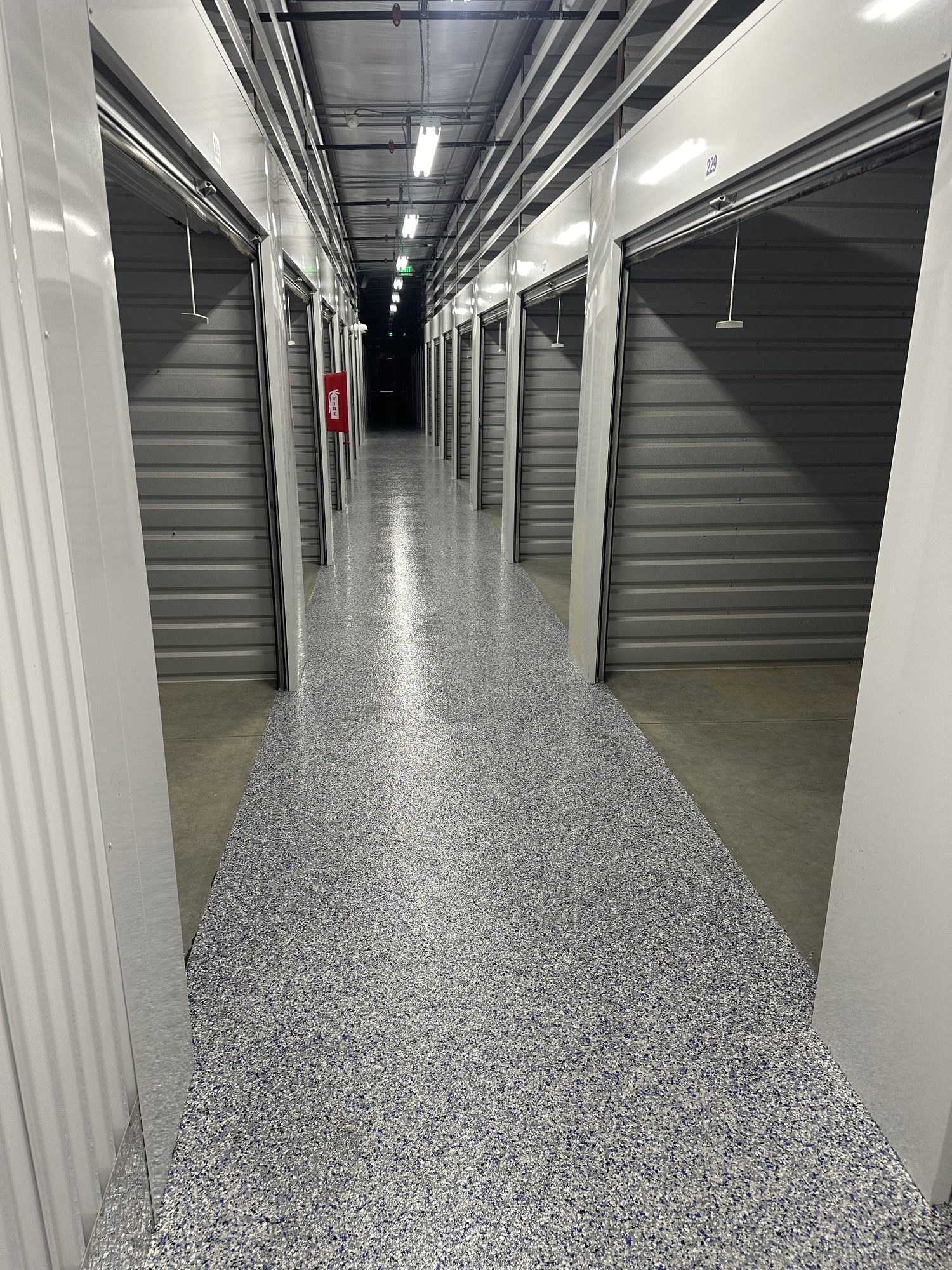 Long storage facility corridor with a gray flake epoxy floor and lit ceiling, Huntsville, AL