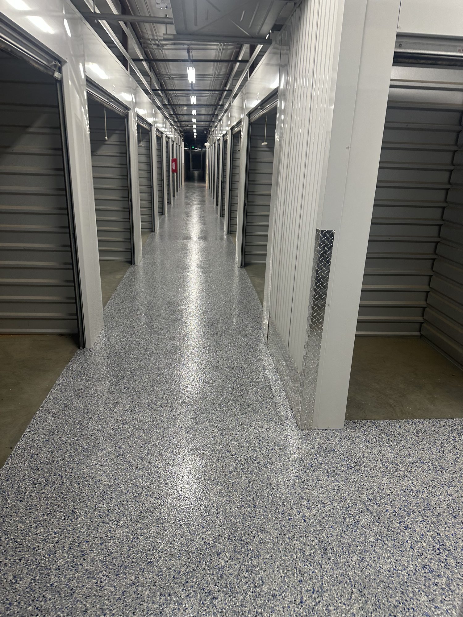 Storage facility hallway, gray flake epoxy floor meeting bare concrete at the edge, Huntsville, AL