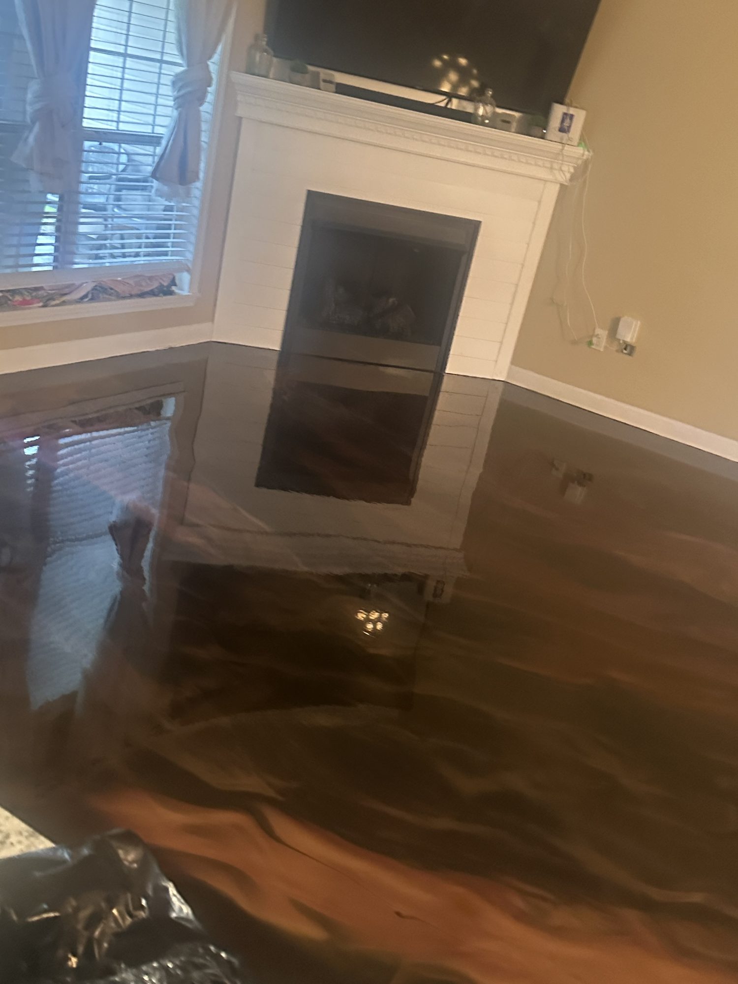 Dark metallic epoxy floor reflecting a white fireplace surround and television, Huntsville, AL