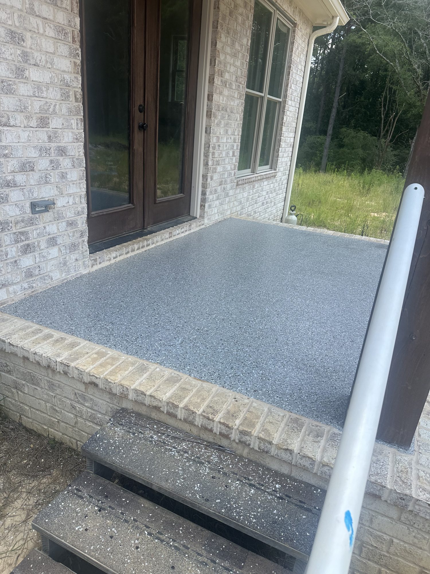 Gray flake epoxy porch slab on a brick home, steps down to the yard, Huntsville, AL