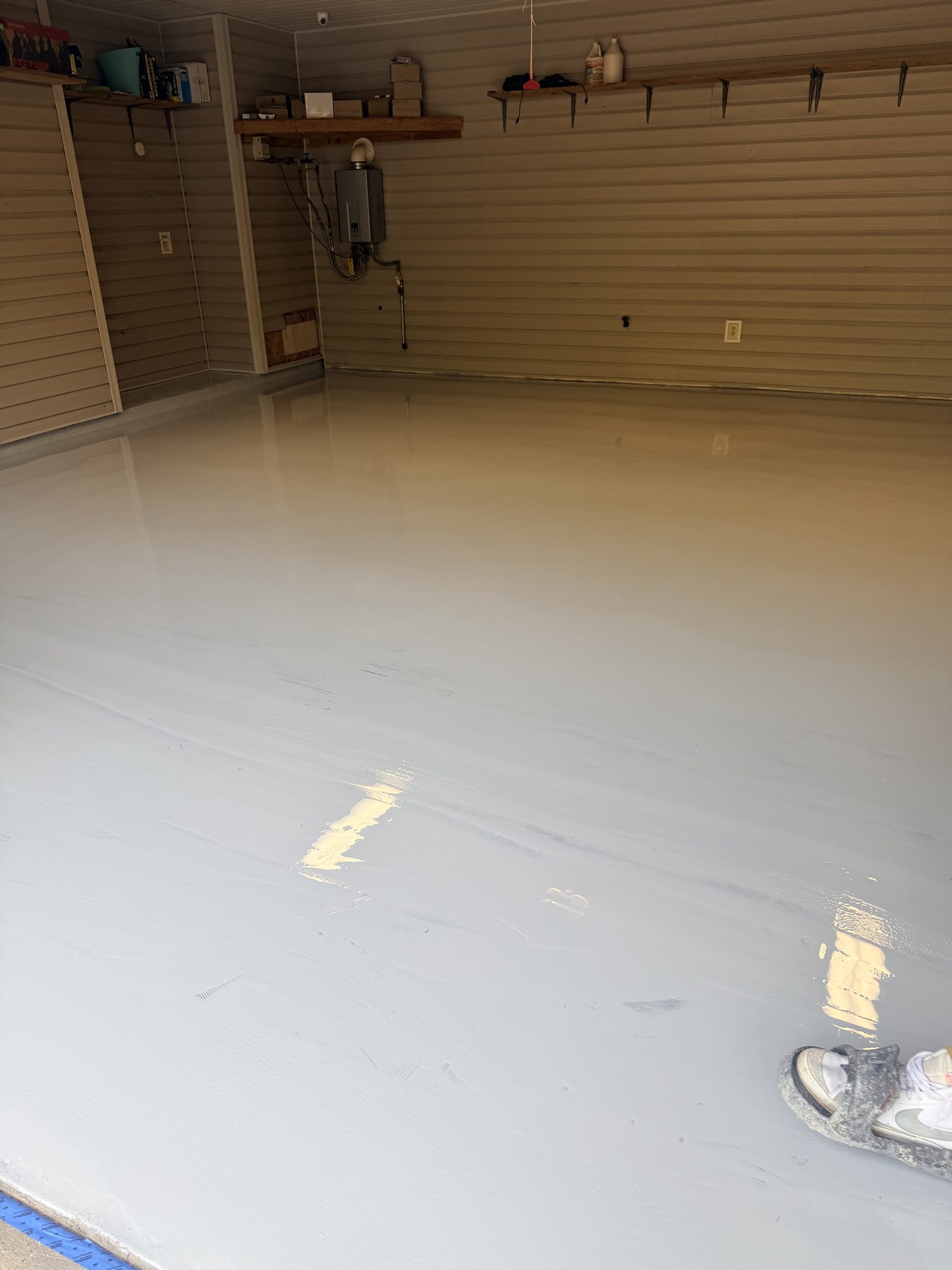 Cream solid color epoxy garage floor reflecting the ceiling, shelving along the back wall, Huntsville, AL