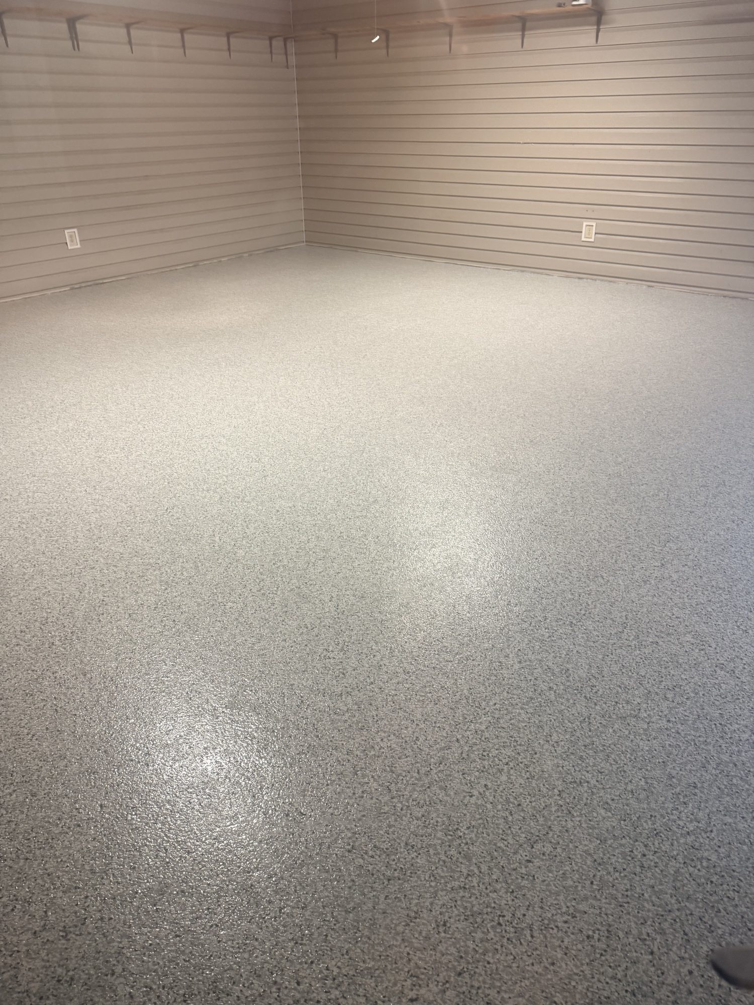 Light gray flake epoxy garage floor in a room with horizontal slat walls, Huntsville, AL