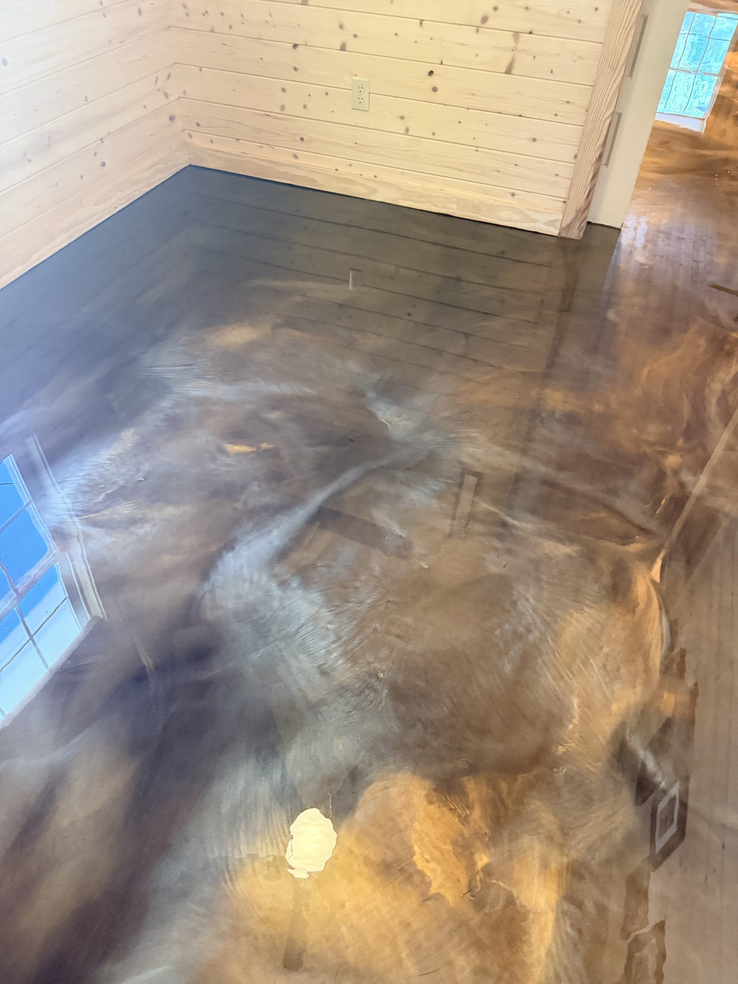 Metallic epoxy floor in warm browns running under a pine wall, wet looking gloss, Huntsville, AL