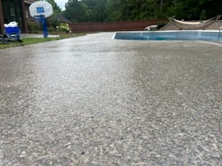 Textured concrete pool deck beside a swimming pool with a basketball hoop and trees, Huntsville, AL