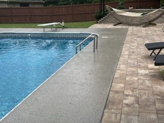 Pool deck coating meeting the pool coping, diving board and paver patio behind, Huntsville, AL