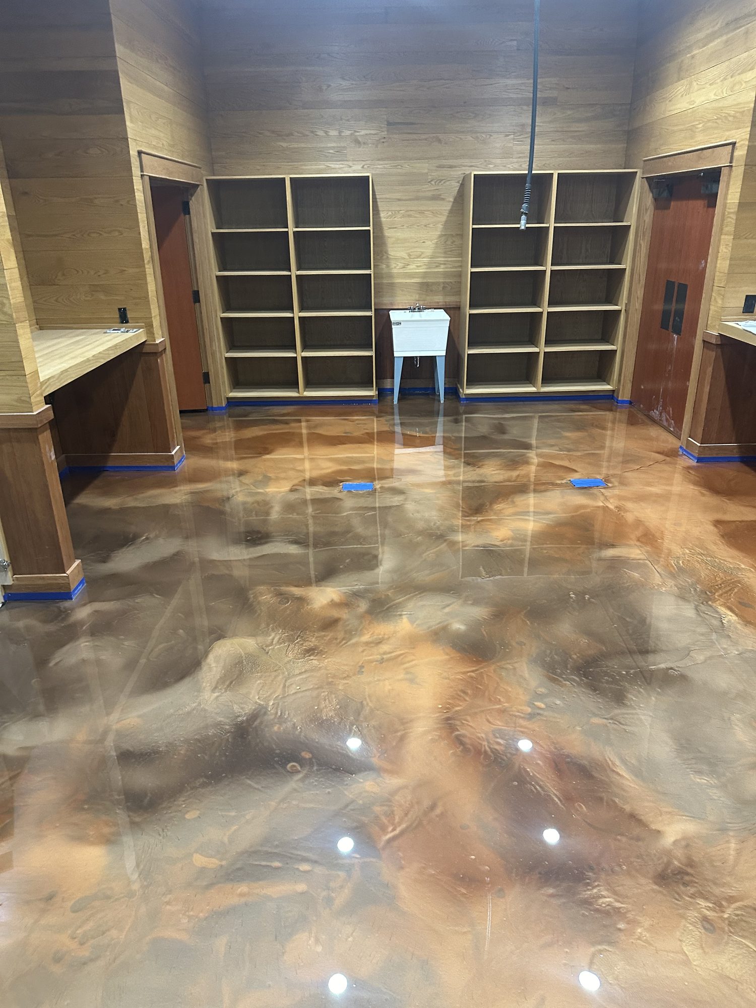 Copper metallic epoxy floor in a wood panelled room with built in shelving, Huntsville, AL