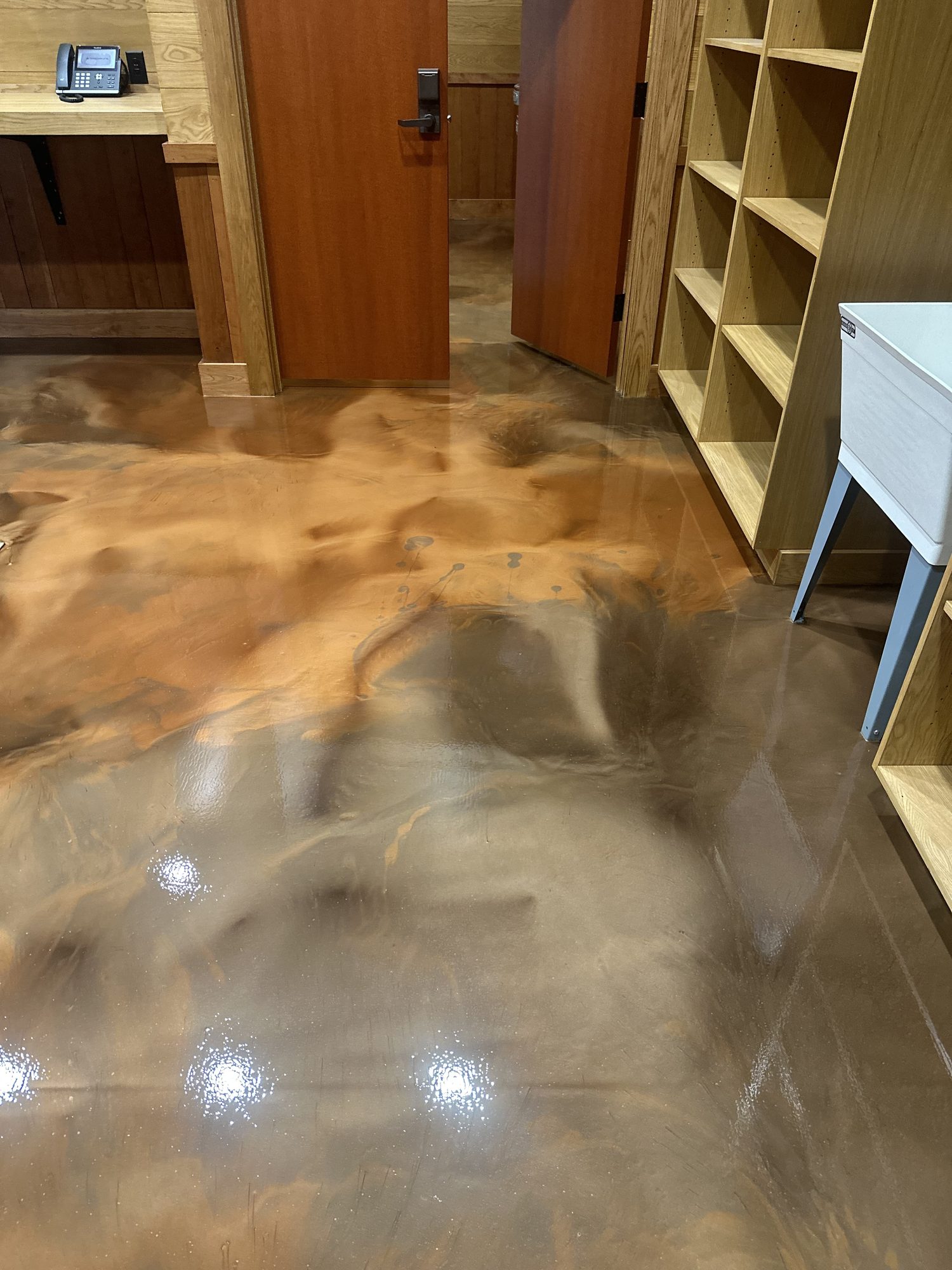 Metallic epoxy floor in tan and gray beside a reception desk and wooden shelving, Huntsville, AL