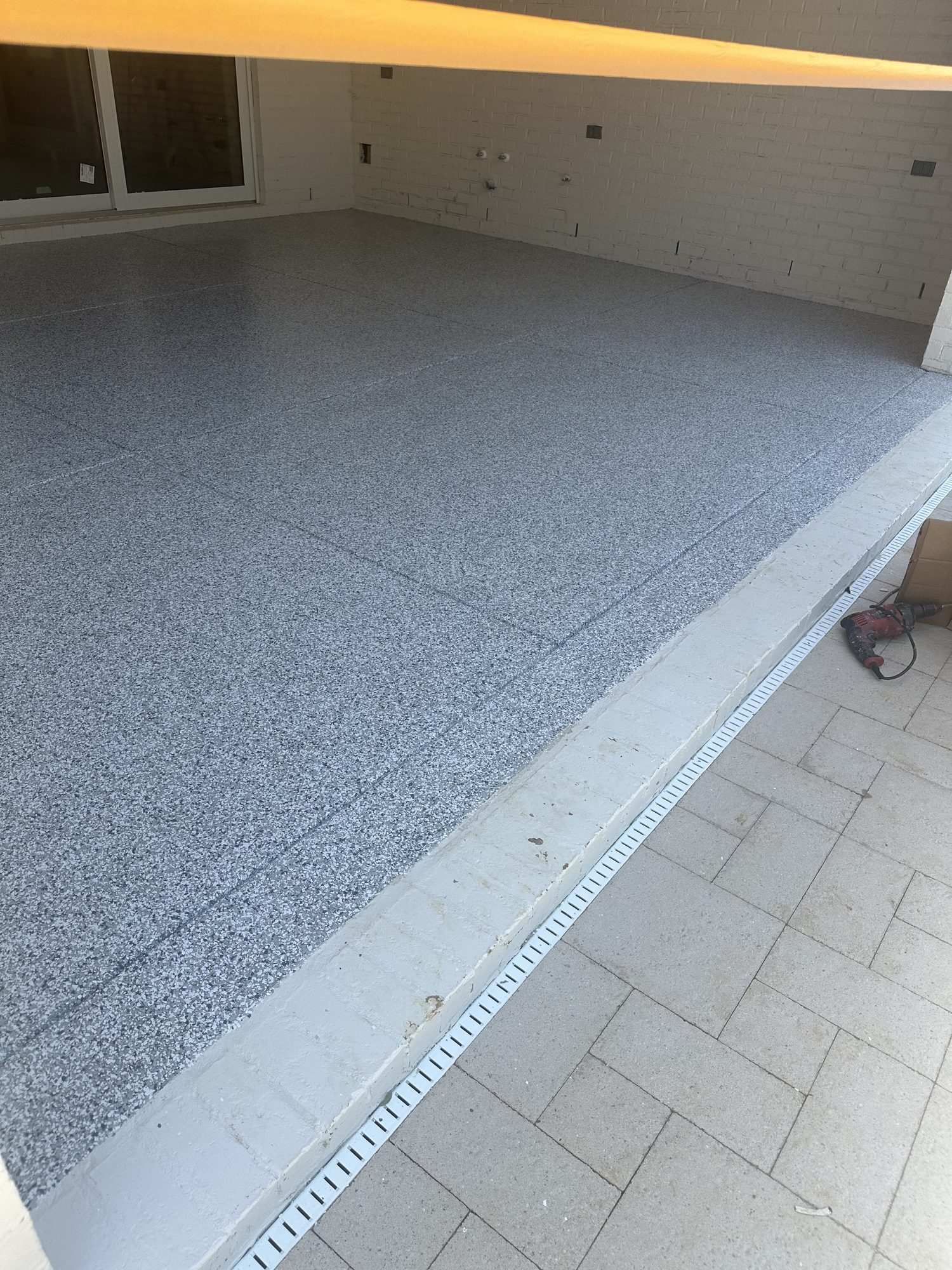 Gray flake epoxy patio slab with a control joint, paver walkway alongside, Huntsville, AL