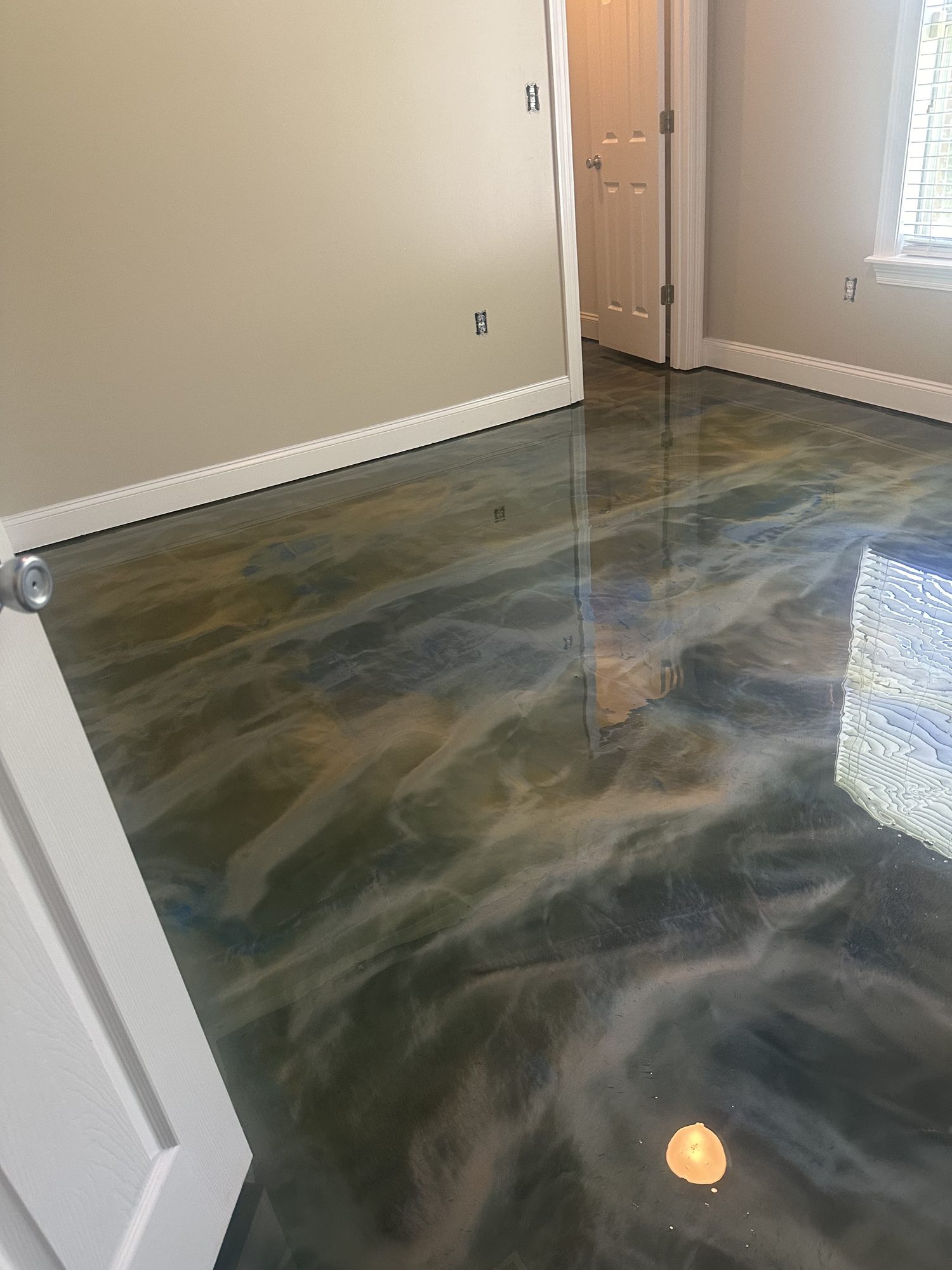 Gray and green metallic epoxy floor in an empty room with white trim and a panelled door, Huntsville, AL