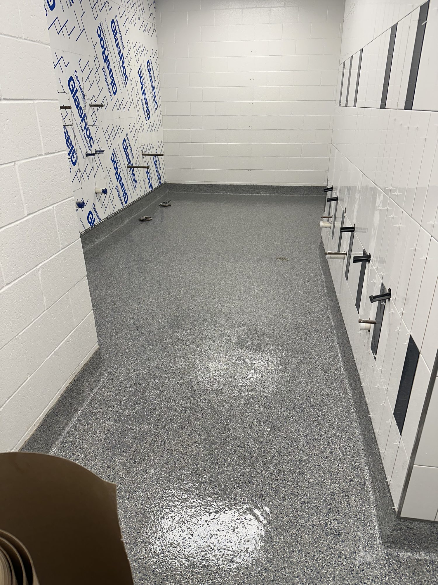 Gray flake epoxy floor in a locker room with white lockers and block walls, Huntsville, AL